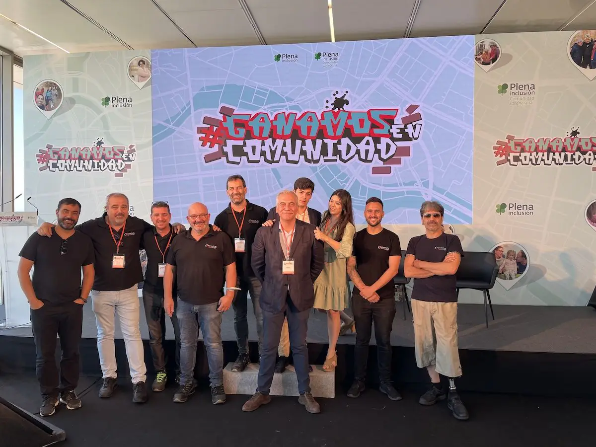 Grupo de personas posando en el escenario de un congreso, ante una pantalla