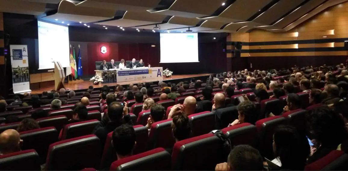 Sala de congresos llena de público, con la mesa presidencial al fondo